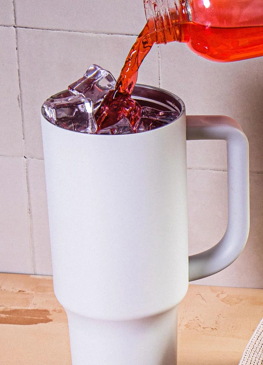 A red Flavor Aid Singles To Go drink poured over ice into a tumbler