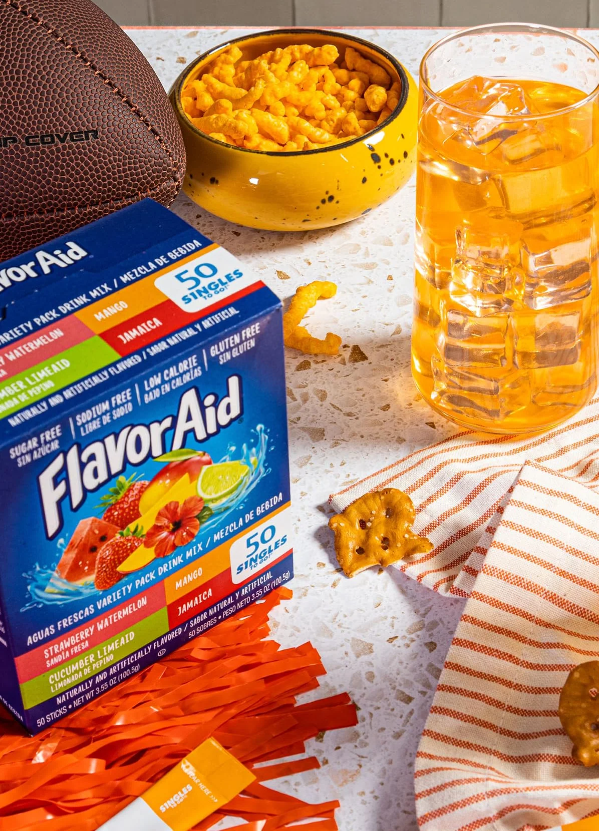 Two glasses of orange Flavor Aid Mango drink over ice beside the Aguas Frescas variety box