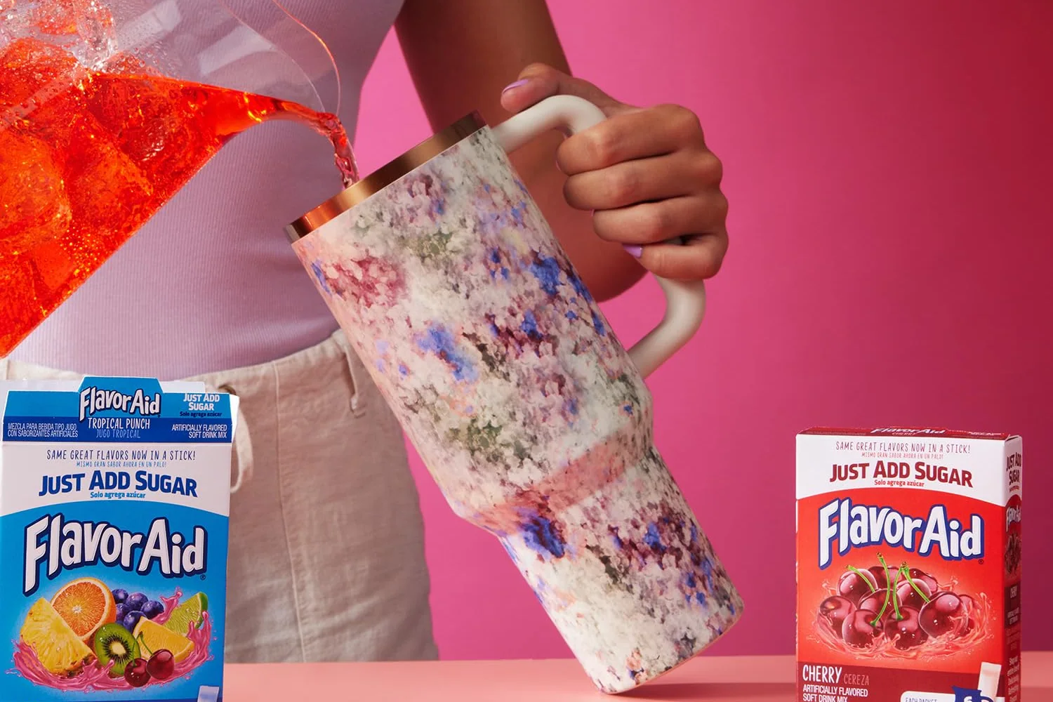 Red Flavor Aid poured from a glass pitcher into a tumbler, Pitcher Packs cartons on the counter